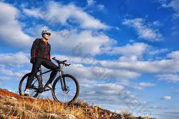 穿着黑色夹克的骑车人骑着自行车下山。极限运动概念。文本的空间。