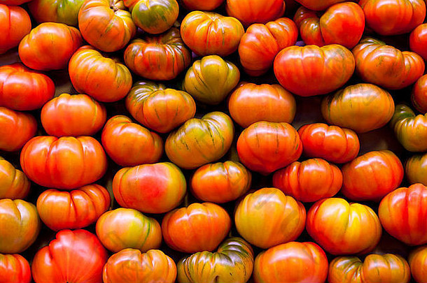许多红色的西红柿，有些有绿色的部分，排列成西红柿墙