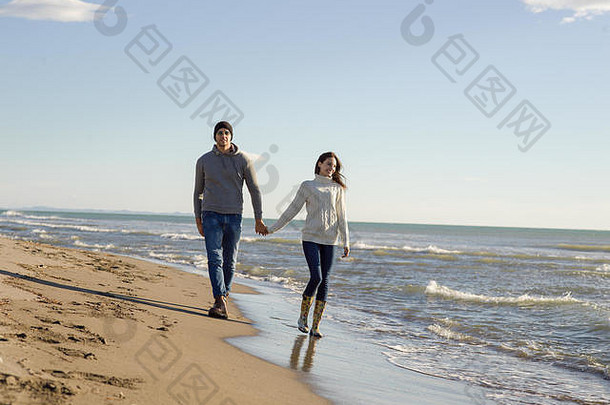 年轻的夫妇有趣的走拥抱海滩秋天阳光明媚的一天