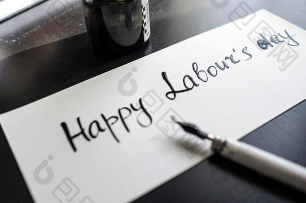 “劳动节快乐”书法和贺卡。用书法笔的左视图。