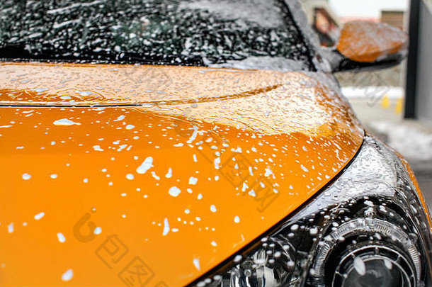 黄色的车前面覆盖洗发水泡沫洗洗车