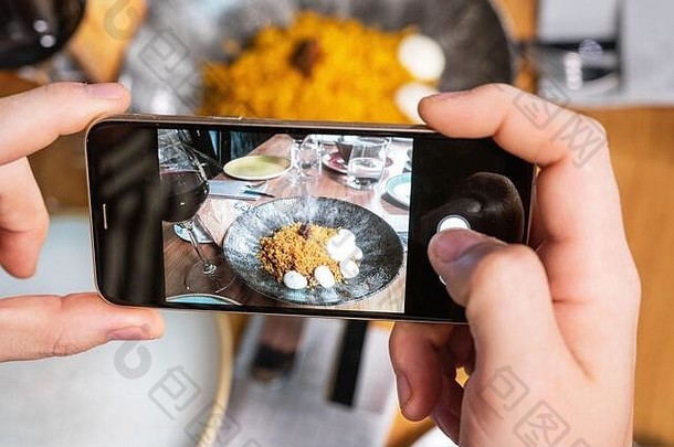 男子手持智能手机在餐厅或咖啡馆拍摄食物。高质量照片