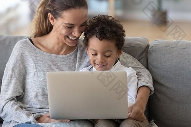 微笑的母亲和非洲裔美国儿子在家使用笔记本电脑
