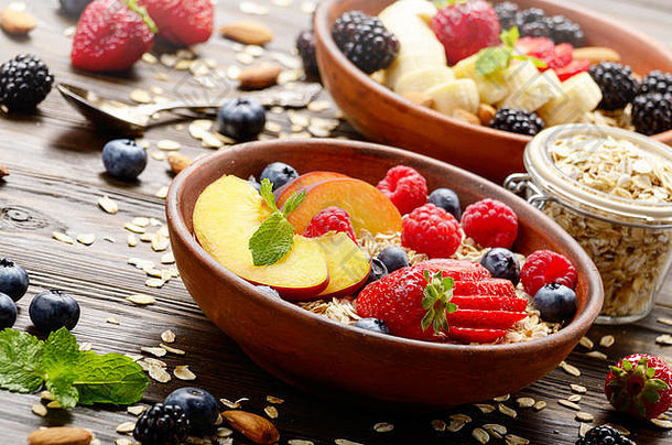 木制厨房餐桌上的粘土盘中有桃子、草莓、杏仁和黑莓等果味健康的<strong>慕斯</strong>利