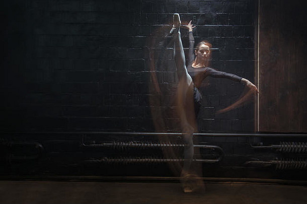 年轻的体操运动员在黑暗的背景下展示她的绳线