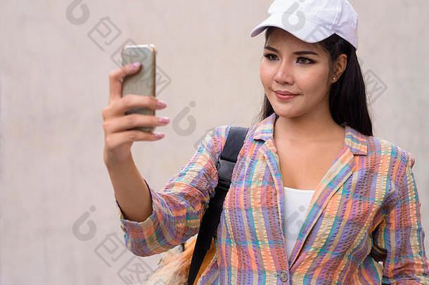 年轻的美丽的亚洲女人移动电话在户外