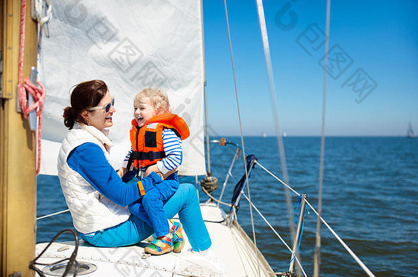 母亲和婴儿在海上的游艇上航行。一家人在船上航行。妈妈和孩子穿着安全的救生衣在远洋轮船上旅行。父母和孩子都喜欢游艇