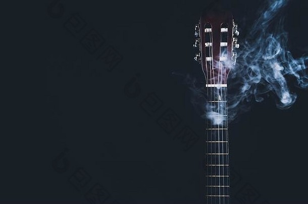 黑色背景上烟雾中的吉他。有声乐器。吉他颈上的弦