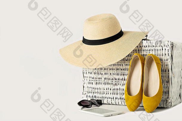 白色柳条手提箱、女帽、太阳镜、黄色鞋子和电子书。