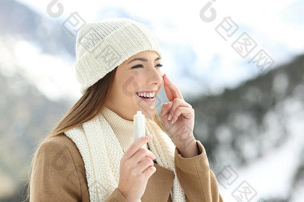 冬天，一位女士在雪山上用保湿霜给脸上的皮肤补水