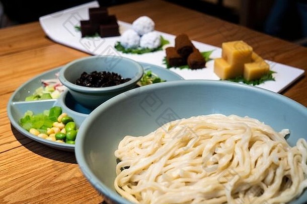 桌子上放着扎江面（中国面条，有酱油和各种配菜）。它是传统北京菜之王