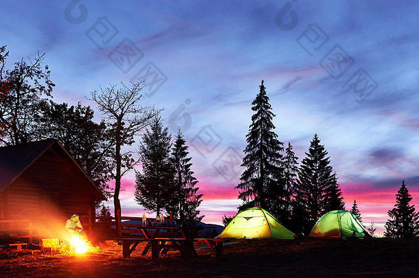 夜间露营。游客们在明亮的帐篷和木屋附近的篝火旁休息，在充满星星和银河的令人惊叹的夜空<strong>下</strong>
