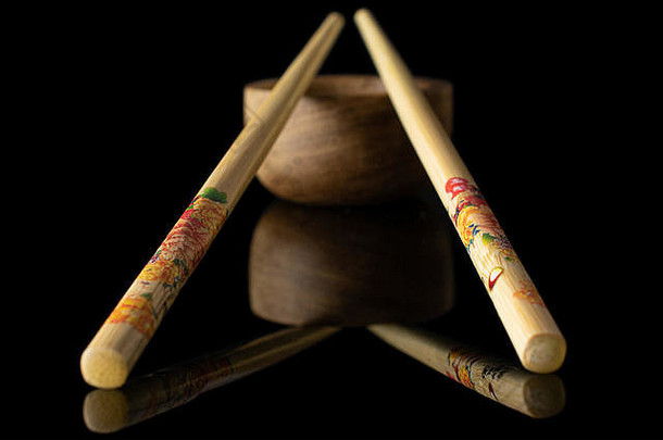 一组两支全彩亚洲棕色筷子，木质碗隔离在黑色玻璃上
