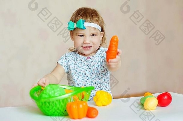 在家里或幼儿园在室内玩耍的小女孩。可爱的微笑着<strong>切塑料</strong>蔬菜的小孩。孩子们的健康生活方式。