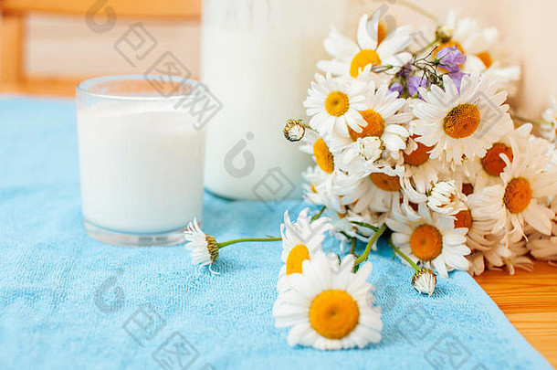 简单时尚的木制厨房，桌上放着一瓶牛奶和玻璃，夏天的花朵甘菊，健康的早晨