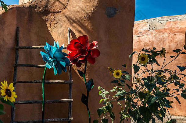 新墨西哥州阿尔伯克基老城的一堵土坯墙上装饰着一个基瓦梯子和<strong>真花</strong>与假<strong>花</strong>的混合物。
