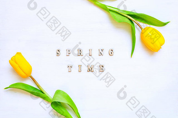 春花背景-由黄色郁金香花和白色背景上的木制铭文春天组成。平面布置，俯视图，sp