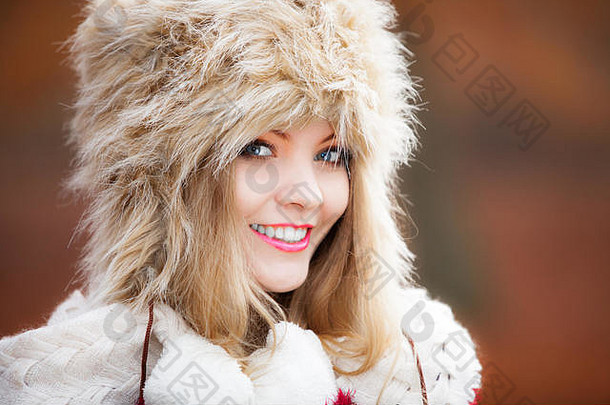 冬季时尚。特写微笑的年轻女子穿着时尚的<strong>冬季服装</strong>皮帽户外肖像