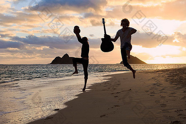 夏威夷海滩日出时，一对孪生<strong>兄弟</strong>的剪影，鼓和吉他在空中跳跃
