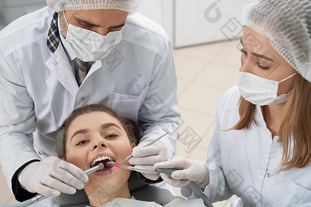 美丽<strong>的</strong>女人白色牙齿说谎牙医椅子打开口相机医生持有恢复仪器口腔学家穿白色医疗面具帽