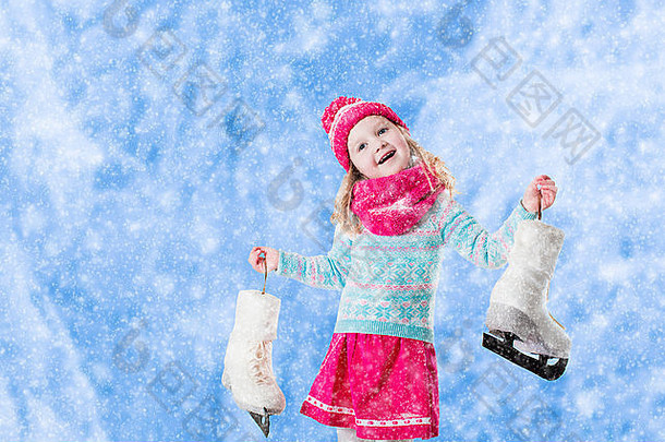 快乐的小女孩在雪地公园里玩滑冰。有孩子的家庭的冬季运动和户外活动