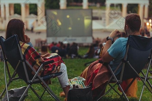 夫妇坐着camp-chairs城市公园电影在户外开放空气电影