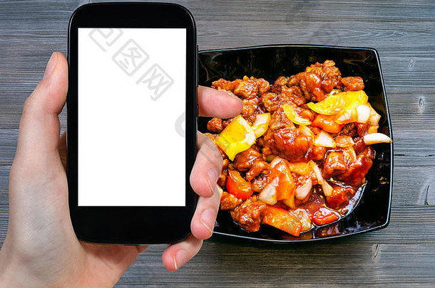 旅游理念-在智能手机上拍摄中国美食甜酸酱猪肉的旅游照片，带有空屏幕，空白位置为