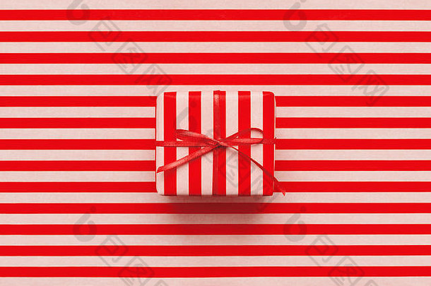 红色和粉色条纹包装纸上的圣诞礼品盒。新年贺卡的最低设计背景。包装日概念。