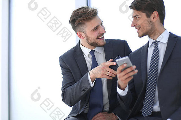 两名微笑的员工在智能手机上讨论视频。