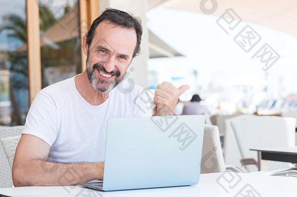 帅哥在餐厅用笔记本电脑指着手，举起手指，脸上带着幸福的笑容
