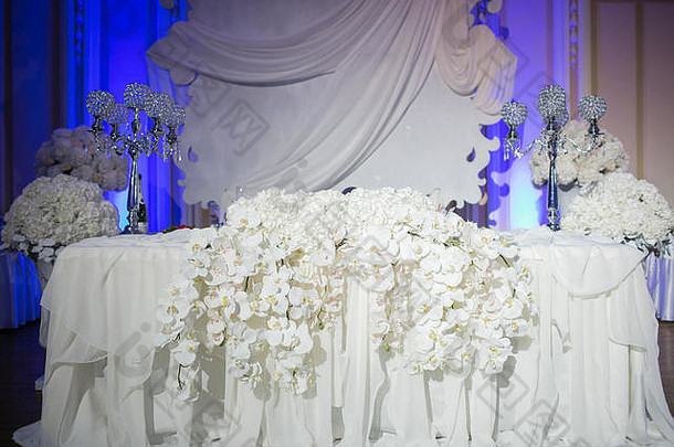 美丽的餐厅内部婚礼餐桌装饰。花花瓶里的白色兰花。豪华烛台