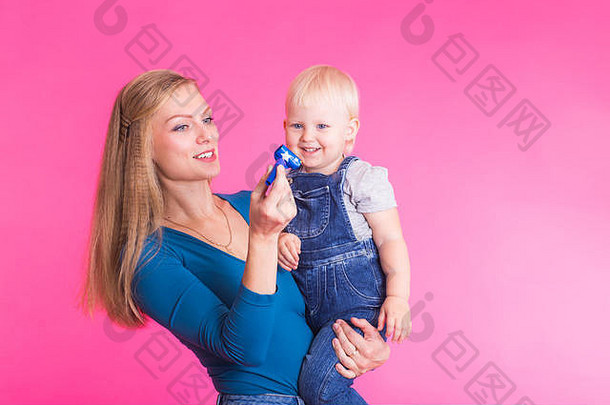 粉红色背景上的有趣家庭。母亲和她的女儿是一个女孩。妈妈和孩子玩得很开心。