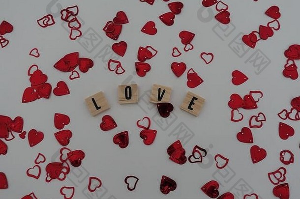 木制工艺字母，在白色背景上用红心五彩纸屑拼写爱情。爱情、浪漫、婚礼、订婚、周年纪念和情人节的概念
