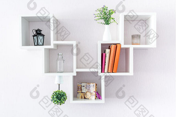 一个现代化的白色书架，白色的墙上有一些东西和一朵花。极简主义风格。