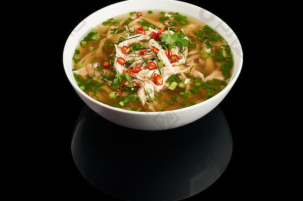 在黑色反射背景上分离的越南鸡肉面条汤Pho Ga板