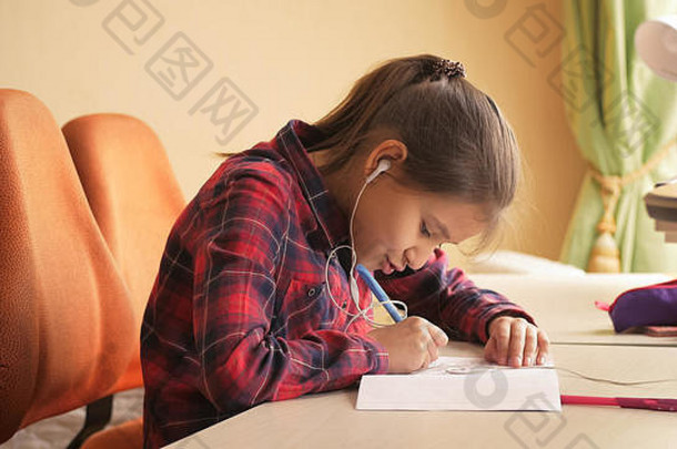 十几岁的女孩一边做作业一边听音<strong>乐</strong>一边唱歌的色调照片