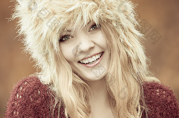秋冬时尚。特写快乐的年轻女子穿着时尚的<strong>冬季服装</strong>皮帽户外肖像