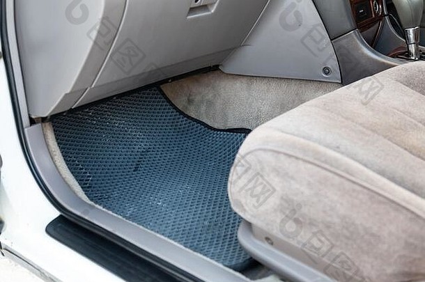 在车间清洁乘客座椅下的黑色橡胶汽车地板垫，以便对车辆进行干洗。汽车服务业。内河