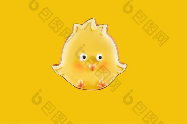 涂有黄色糖衣的复活节鸡形状的姜饼饼干。隔离在黄色背景上。单色和极简主义的概念。