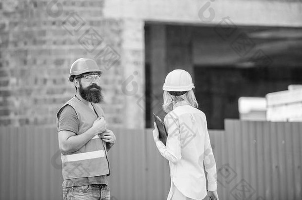 施工现场安全检查。讨论项目进展。女检查员和留胡子的野蛮建筑工人讨论施工进度。建设<strong>工程监理</strong>。安全检查员概念。