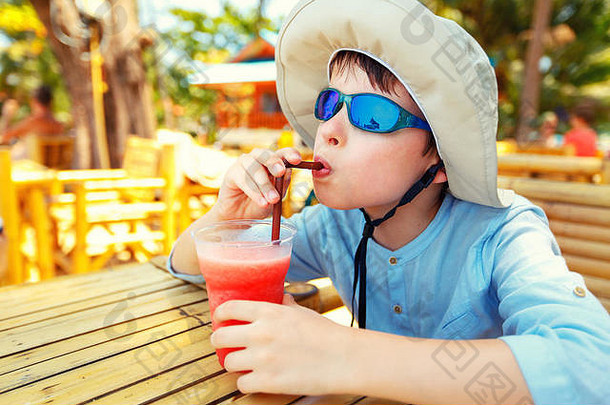 在热带海滩度假村喝西瓜汁的可爱小男孩