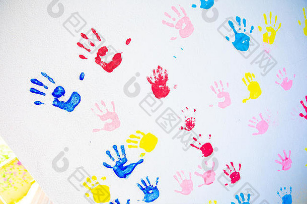 在白色墙壁背景上隔离的手的彩色手印。学校墙上的儿童手印