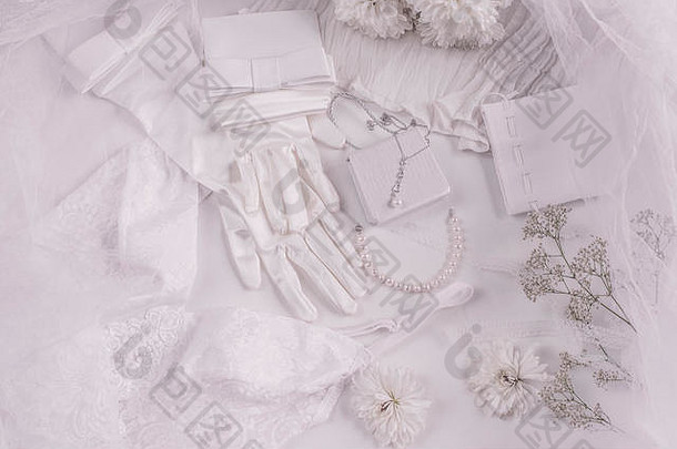 婚礼背景的白色新娘配件，包括珍珠、白色缎带和蕾丝、手套、手镯、时尚博客的平面布置、俯视图