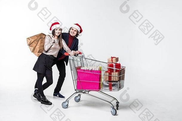 年轻的夫妇持有购物袋礼物推卡车礼物孤立的白色背景圣诞节出售