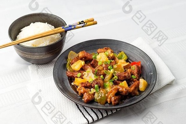 糖醋猪肉中国菜。在炒菠萝、洋葱、辣椒和酱汁中加入油炸肉。糖醋菜在亚洲很常见