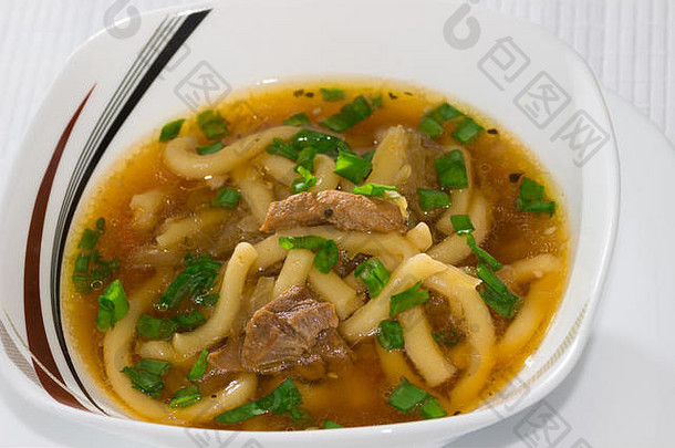 一碗味噌汤，配乌冬面、卷心菜、猪肉和大葱，用筷子夹在竹餐巾上