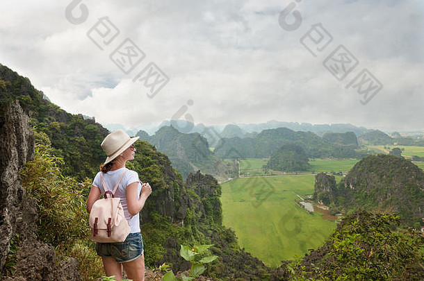 背着背包从山顶欣赏山谷景色的年轻女游客