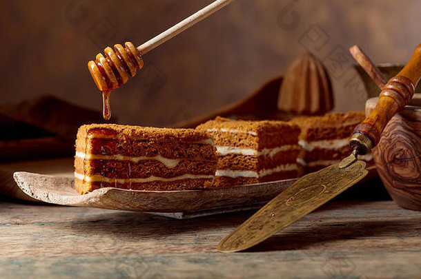 在一张旧木桌上放着的加奶油的分层蜂蜜蛋糕。