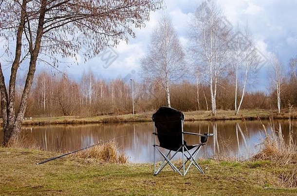 春季钓鱼。湖岸上渔夫的椅子和鱼竿。钓鱼
