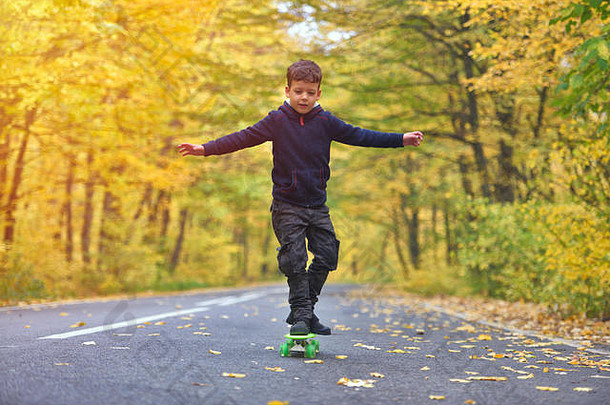 在秋天的环境中玩滑板的小孩